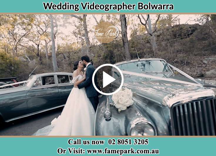 The newly weds kissing near the wedding car Bolwarra NSW 2320